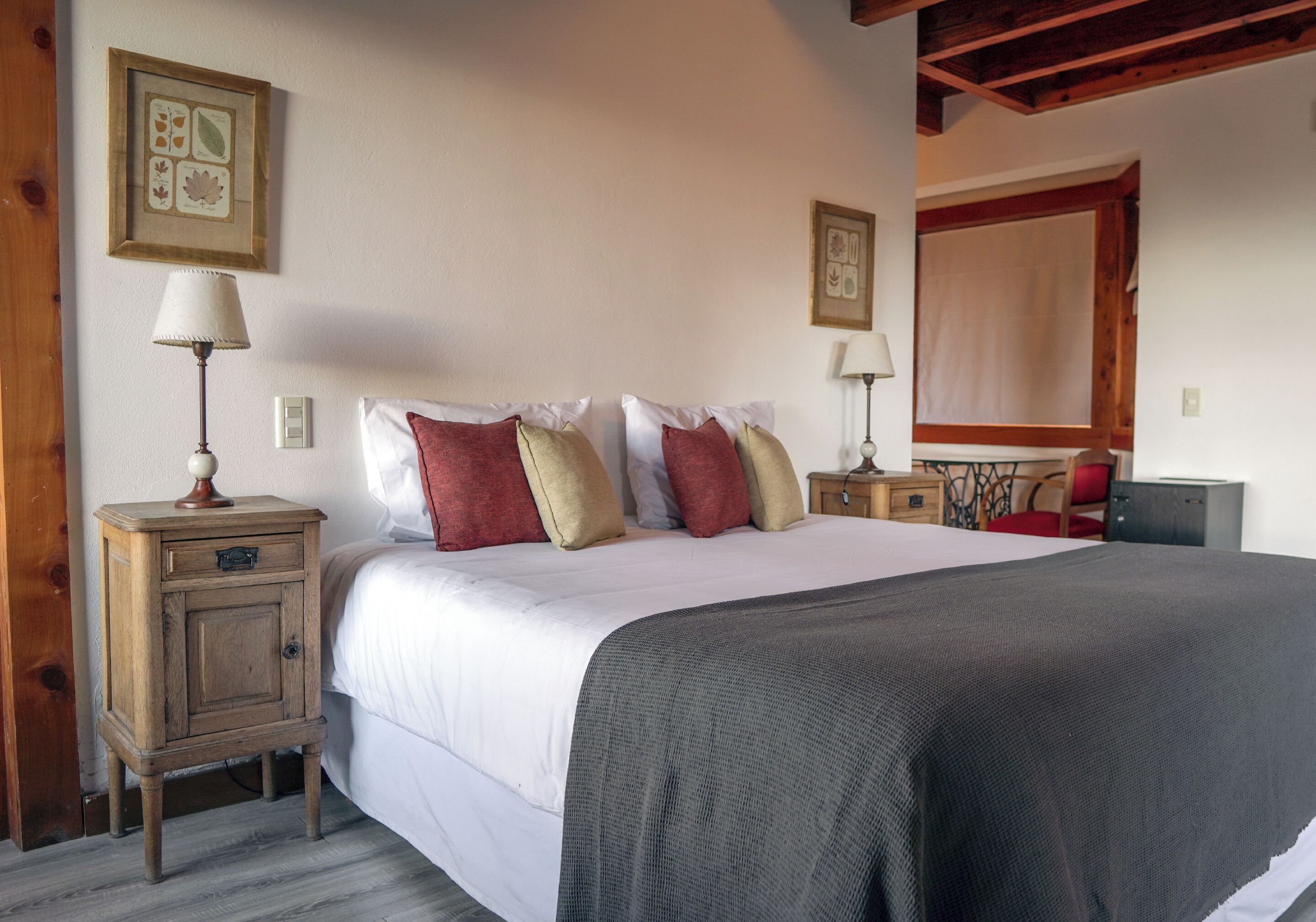 A bedroom with a large bed, two bedside tables, a nightstand, and a mirror.