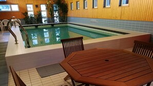 An indoor pool area with a wooden table and chairs, tiled flooring, and wooden walls. - Hostel Sivakka (Kolari)