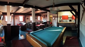 A pool table in a room with a dining area, kitchen, and a view of the outside. - Hostel Sivakka (Kolari)