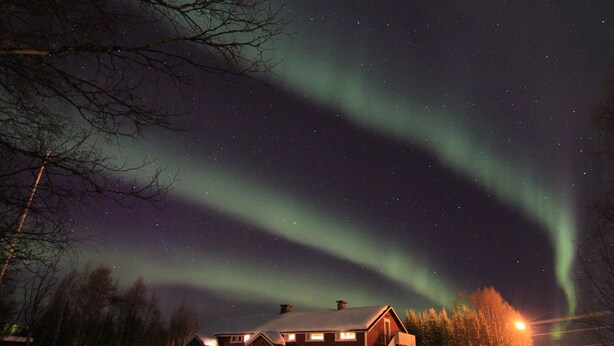A snow-covered landscape with a wooden house and a clear night sky. - Hostel Sivakka (Kolari)