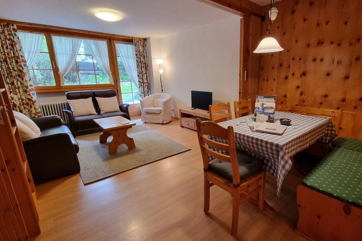 Una habitación acogedora con una mesa de madera, un sofá y un televisor.