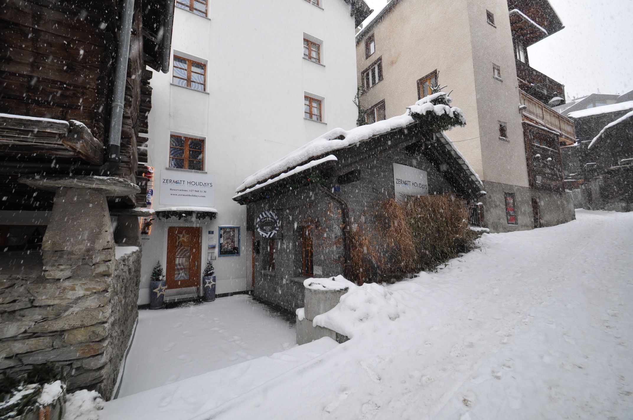 Een met sneeuw bedekt gebouw met een bord voor Zermatt Holidays.