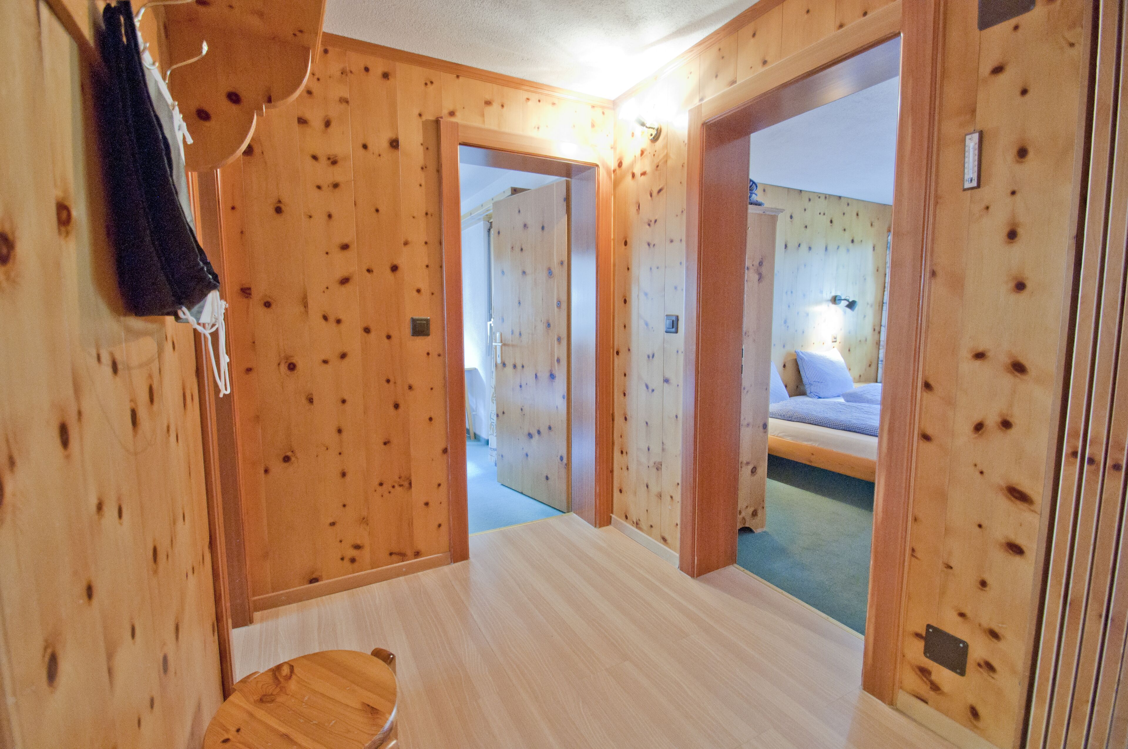 A wooden interior with a visible door leading to a bedroom.