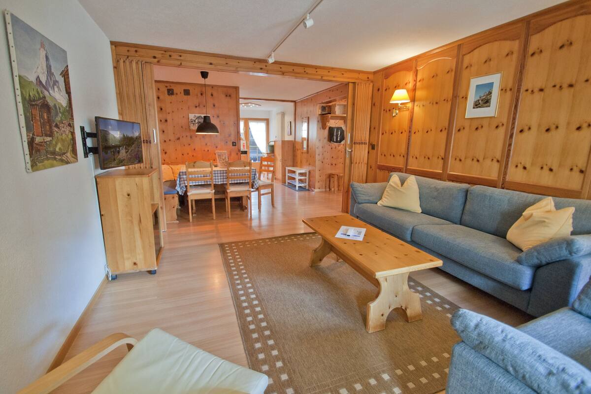 Una sala de estar acogedora con sofá, una mesa de centro y un comedor con sillas y una mesa.
