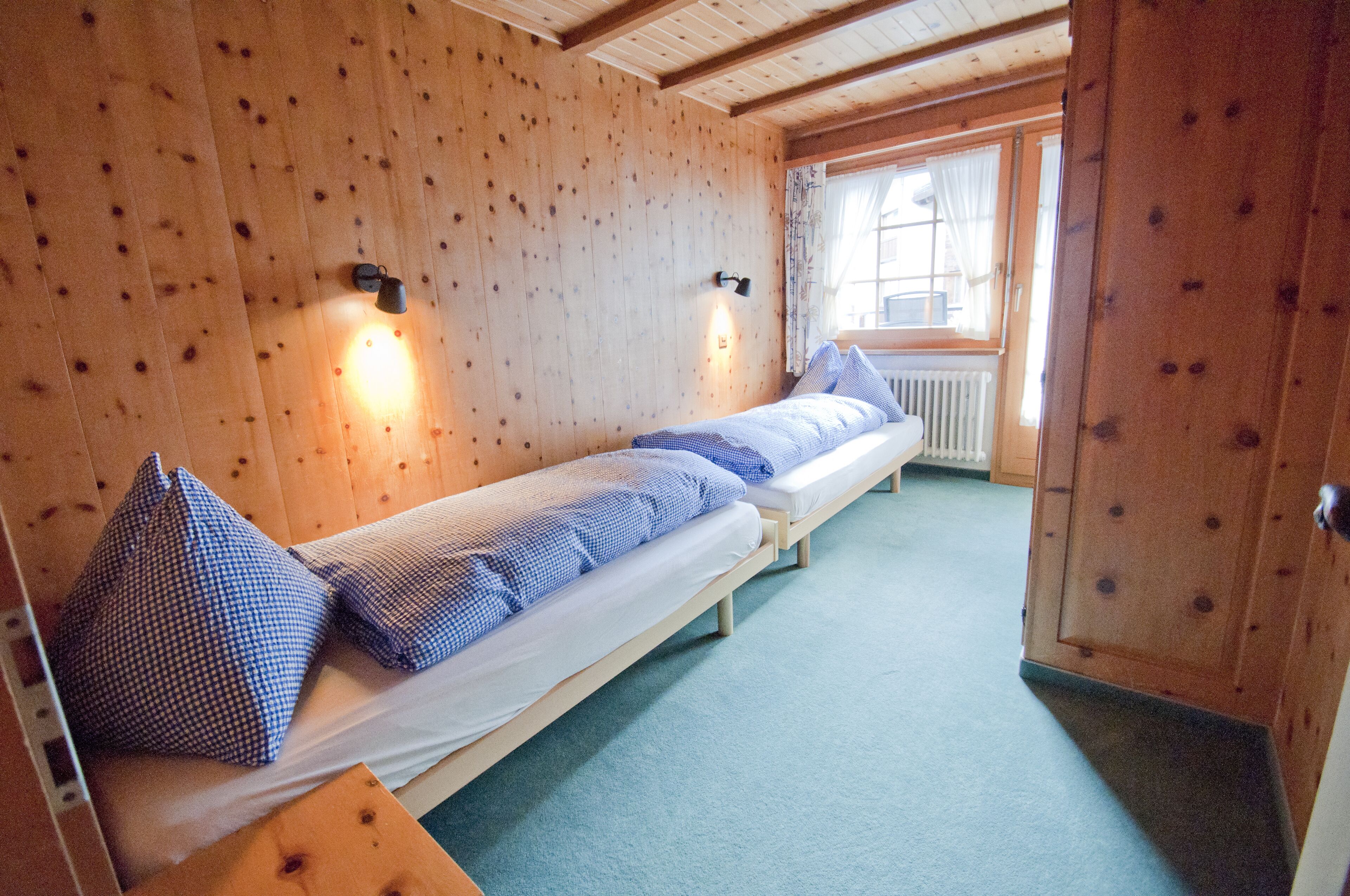 Una habitación con dos literas de madera, una ventana con cortinas y un radiador.