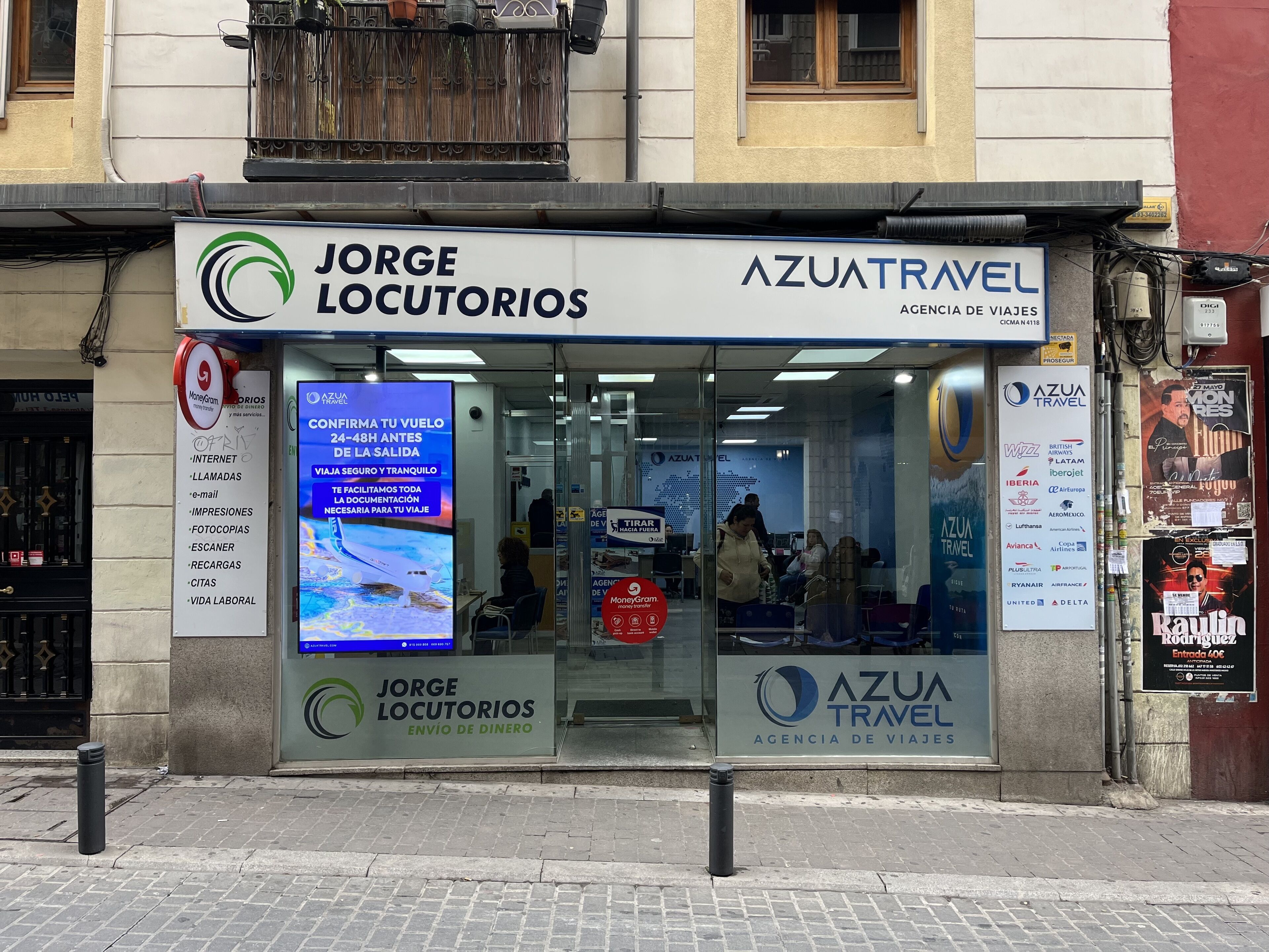 Una agencia de viajes llamada 'Jorge Locutórios' con un letrero que dice 'AzuaTravel' y un escaparate que muestra gente en el interior.