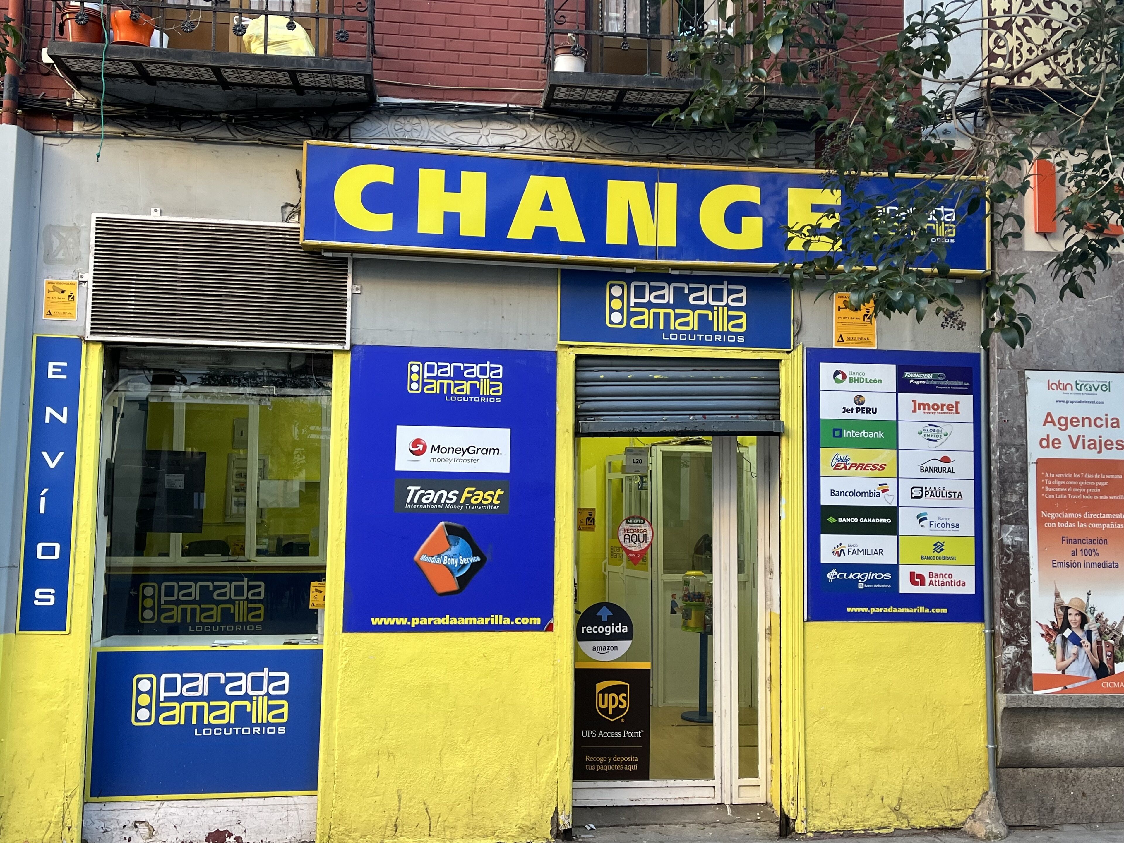 A storefront with a prominent 'CHANGE' sign, indicating a currency exchange service. The facade displays multiple logos of financial institutions and services such as MoneyGram, Trans Fast, and UPS Access Point.