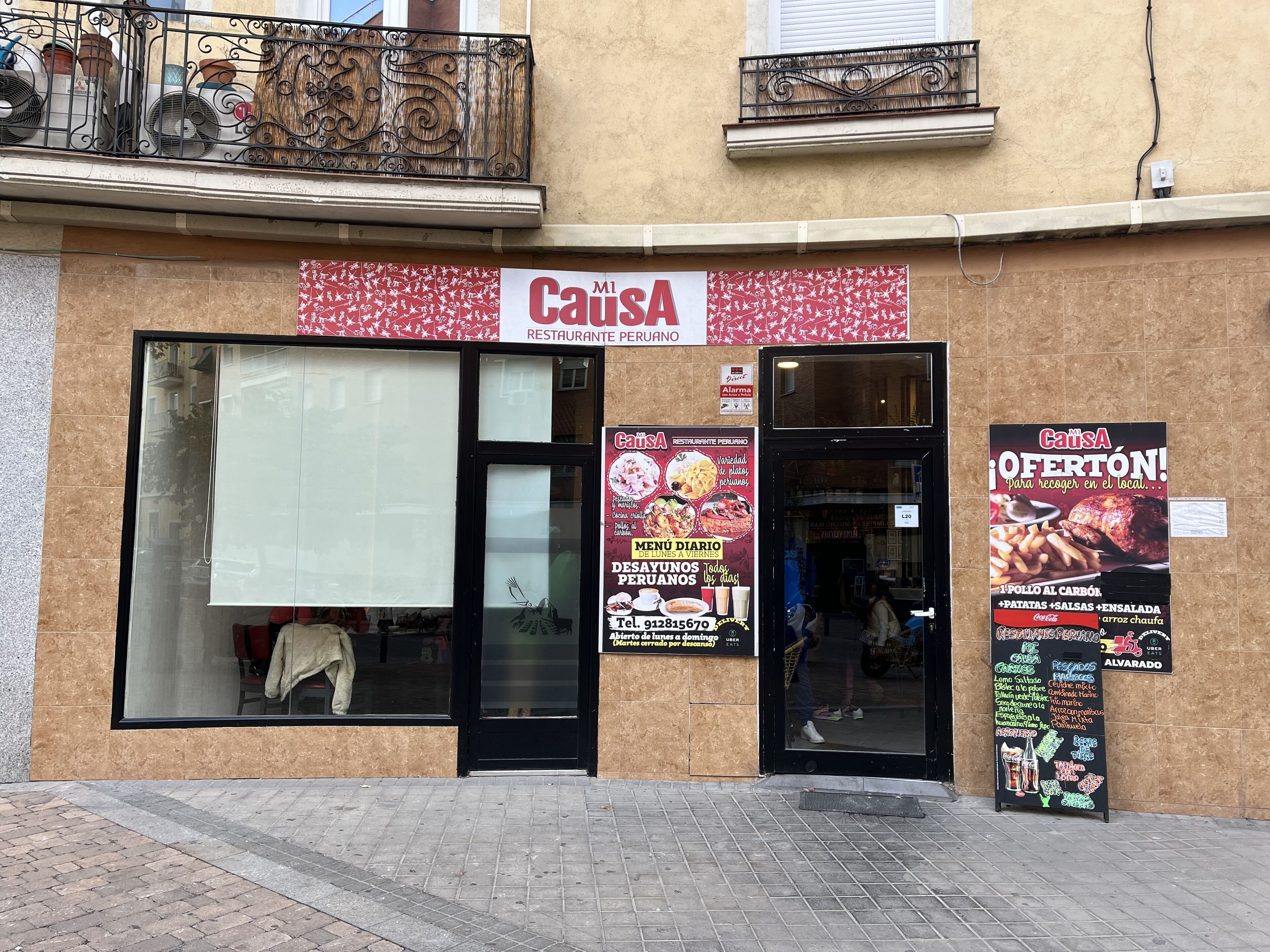 A restaurant named "Causa" with a large glass window and a black door. There are outdoor seating areas visible through the window.