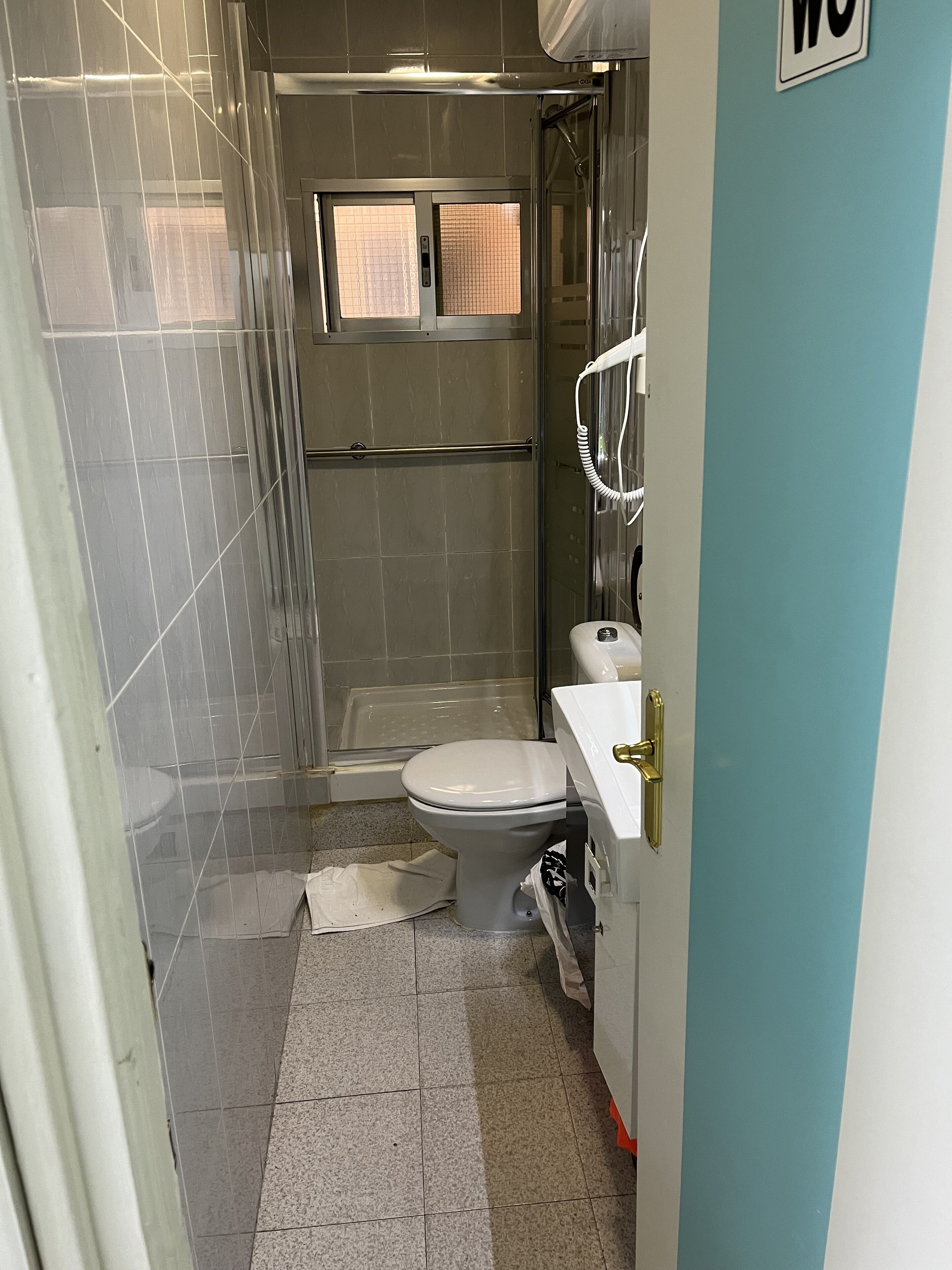 A small bathroom with a toilet, sink, and shower.