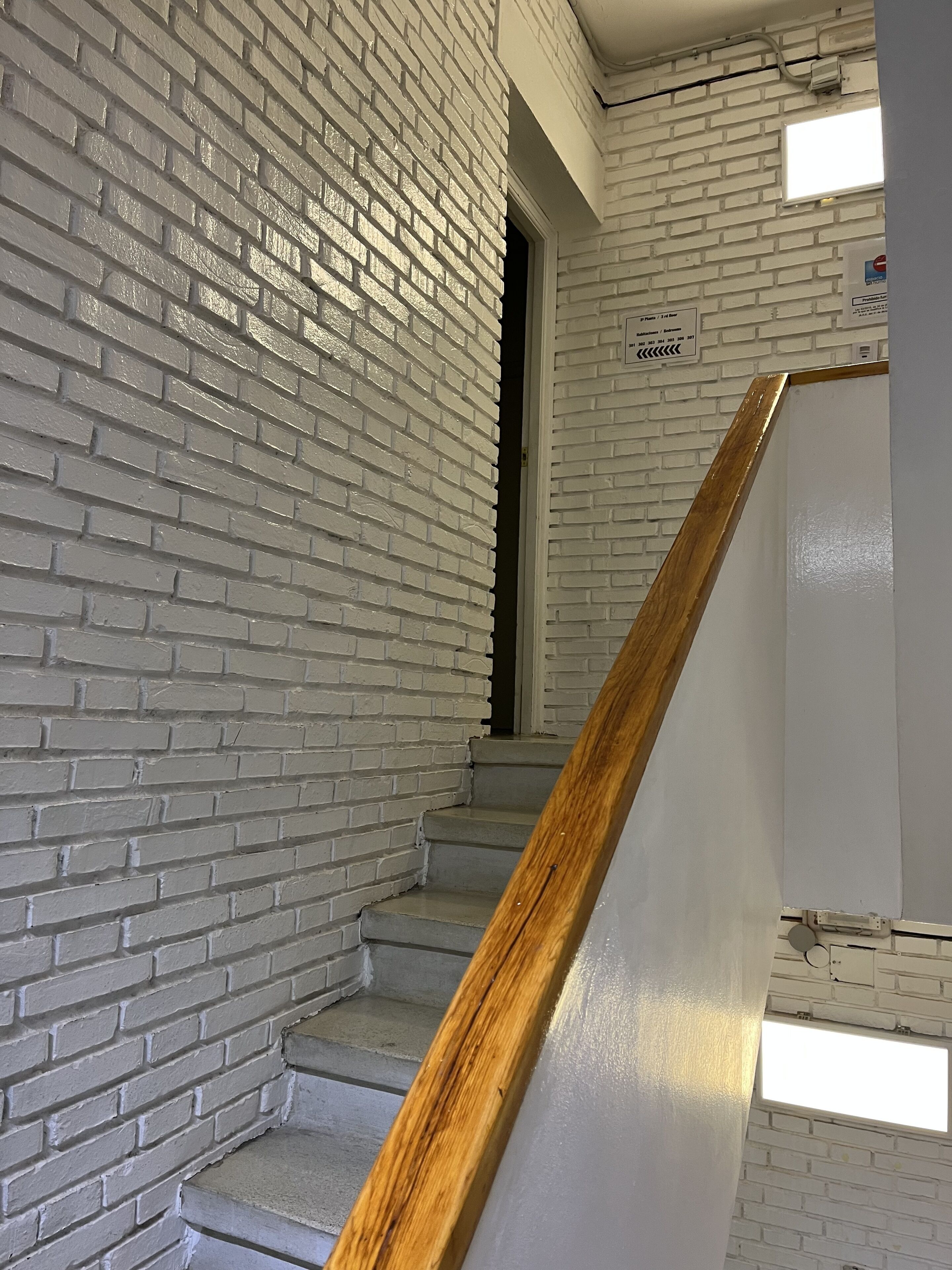 A staircase with white brick walls and wooden handrails.