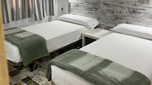 A hotel room with two single beds, a headboard with a textured wall, a window with curtains, and a patterned floor. - Casa de huespedes Almansa (Madrid)