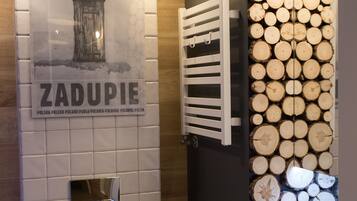 A bathroom with a toilet, a towel rack, and a wall decorated with stacked logs.