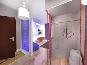 Un interior moderno con una puerta de madera, una pared azul de acento, una pared blanca con un diseño geométrico, un banco rojo y un inodoro blanco.