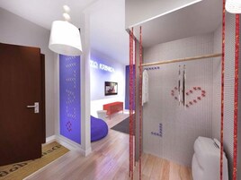 Un interior moderno con una puerta de madera, una pared azul de acento, una pared blanca con un diseño geométrico, un banco rojo y un inodoro blanco.