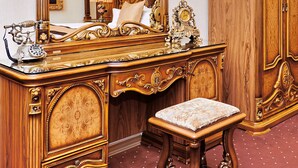 Ein verzierter Holzkonsolen-Schrank mit Spiegel, Telefon und einer Uhr.