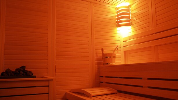 Eine Sauna mit Holzbänken und einer Wandleuchte.