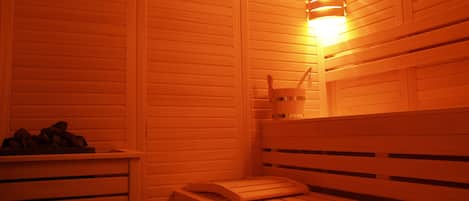 A sauna with wooden benches and a wall-mounted light fixture.