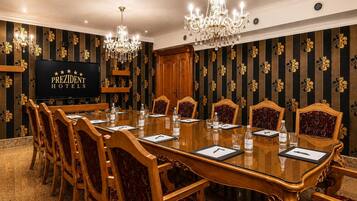 A conference room with a long table, chairs, a television, and chandeliers.