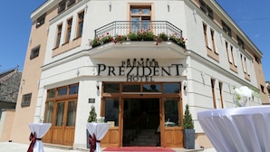 The exterior of the Premier President Hotel with a classic facade, large windows, and a balcony with flowers.