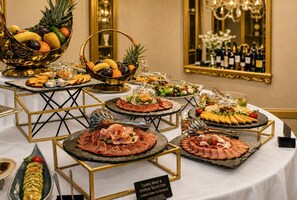 Une table de buffet proposant une variété d’aliments, notamment des charcuteries, des fromages et des fruits.