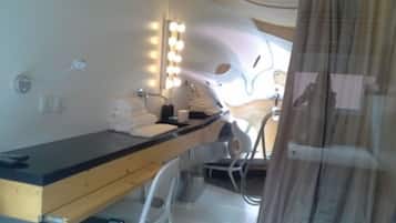 A bathroom with a vanity, towel stack, and a mirror with lights.