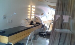 A bathroom with a vanity, towel stack, and a mirror with lights.