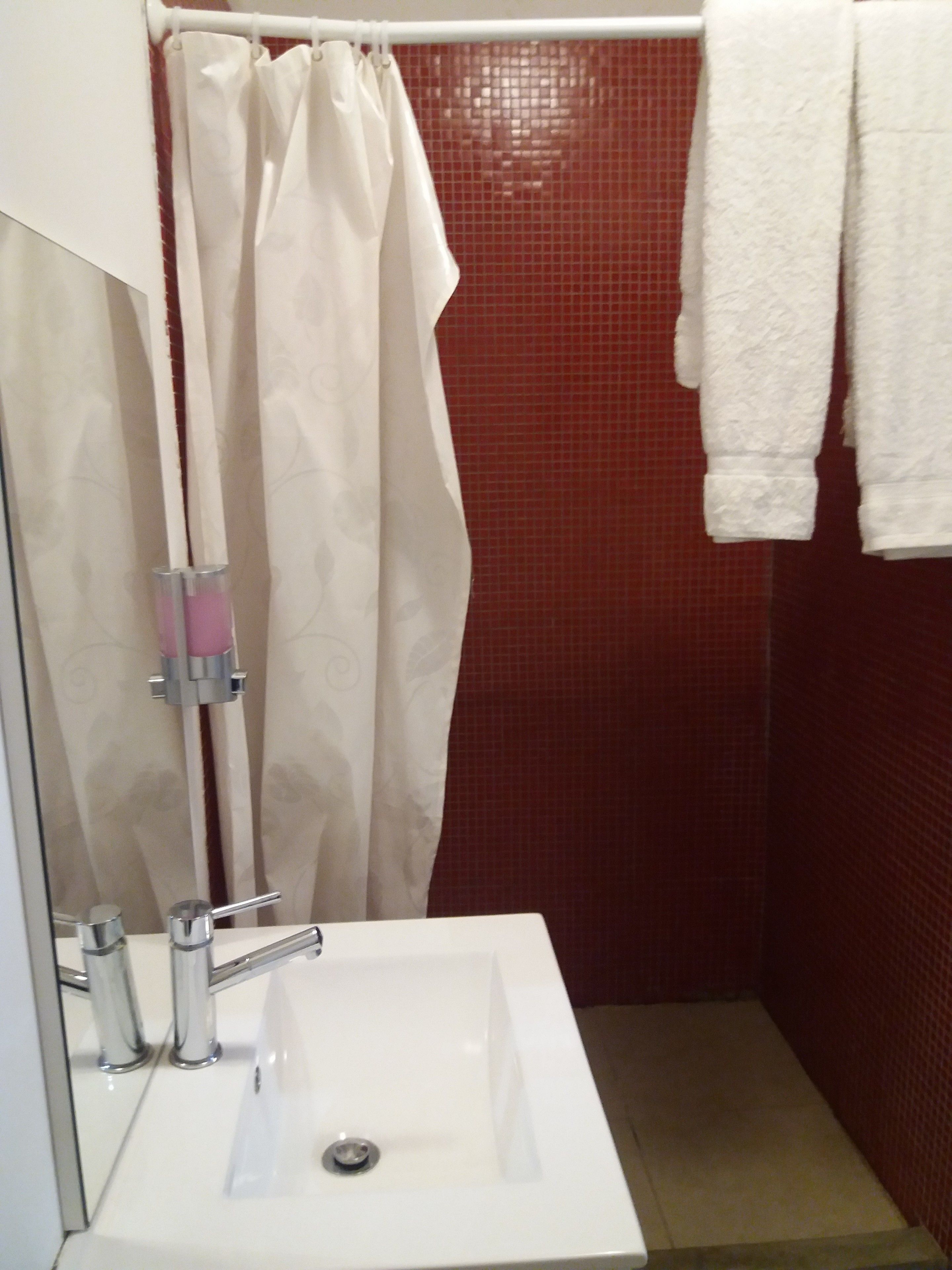 Uma casa de banho com uma pia branca, um separador de chuveiro e uma toalha pendurada na parede.