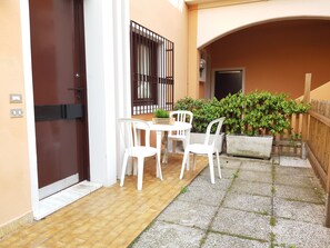 Ein kleiner Patio-Bereich mit Tisch und Stühlen, einem Topfpflanzen und einem Holzzaun.