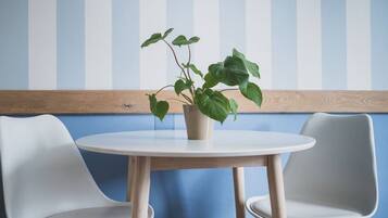 A round table with a potted plant in the center, flanked by two white chairs.