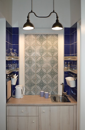 A kitchen with a wooden countertop, two pendant lights, a patterned backsplash, and a sink with a faucet. - Cybulskiego Guest Rooms (Kraków)