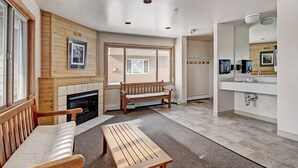 A modern living room with a fireplace, a bench, a coffee table, and a large window. - 522 Watch Hill (Silverthorne)