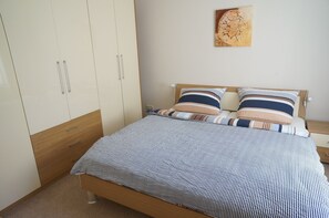 A bedroom with a bed, wooden wardrobe, and a painting on the wall. - 3 wunderschöne Ferienwohnungen Kornhoff (Naumburg)