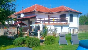 A two-story house with a red-tiled roof, a patio with outdoor furniture, and a small inflatable pool. - Villa Kalin (Veliko Tarnovo)