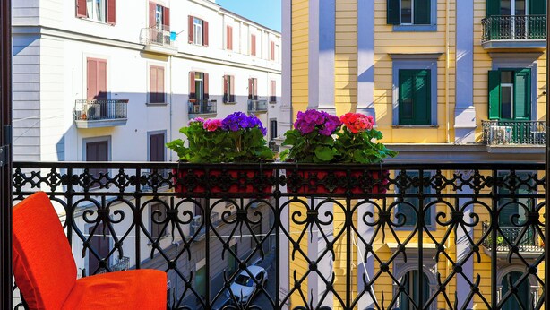 A balcony with wrought iron railings and a red chair. - I Viceré B&B Deluxe (Naples)