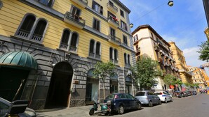 A multi-story yellow building with balconies, parked cars, and a clear sky. - I Viceré B&B Deluxe (Naples)