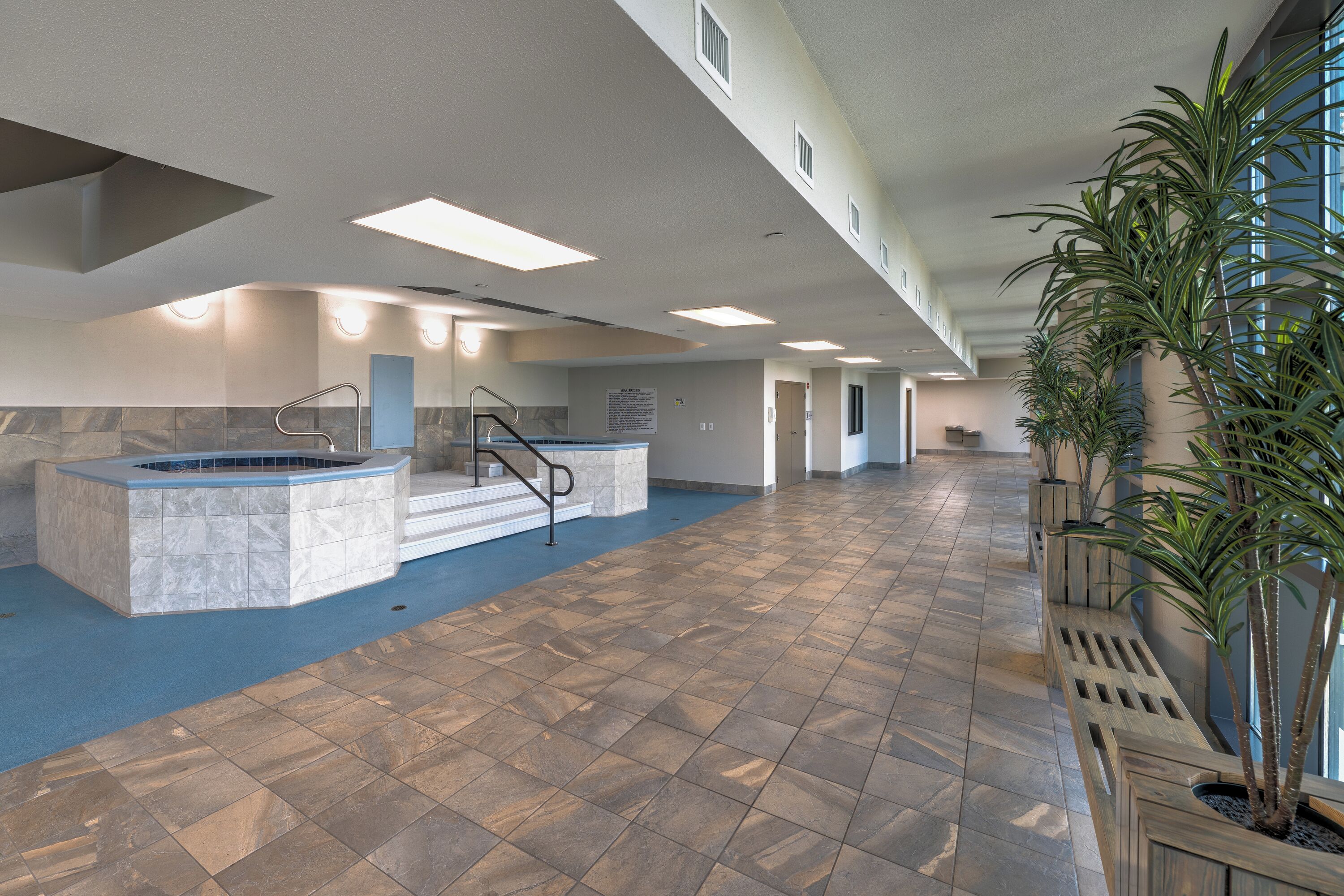 A spacious indoor area with a pool, a staircase, and potted plants.