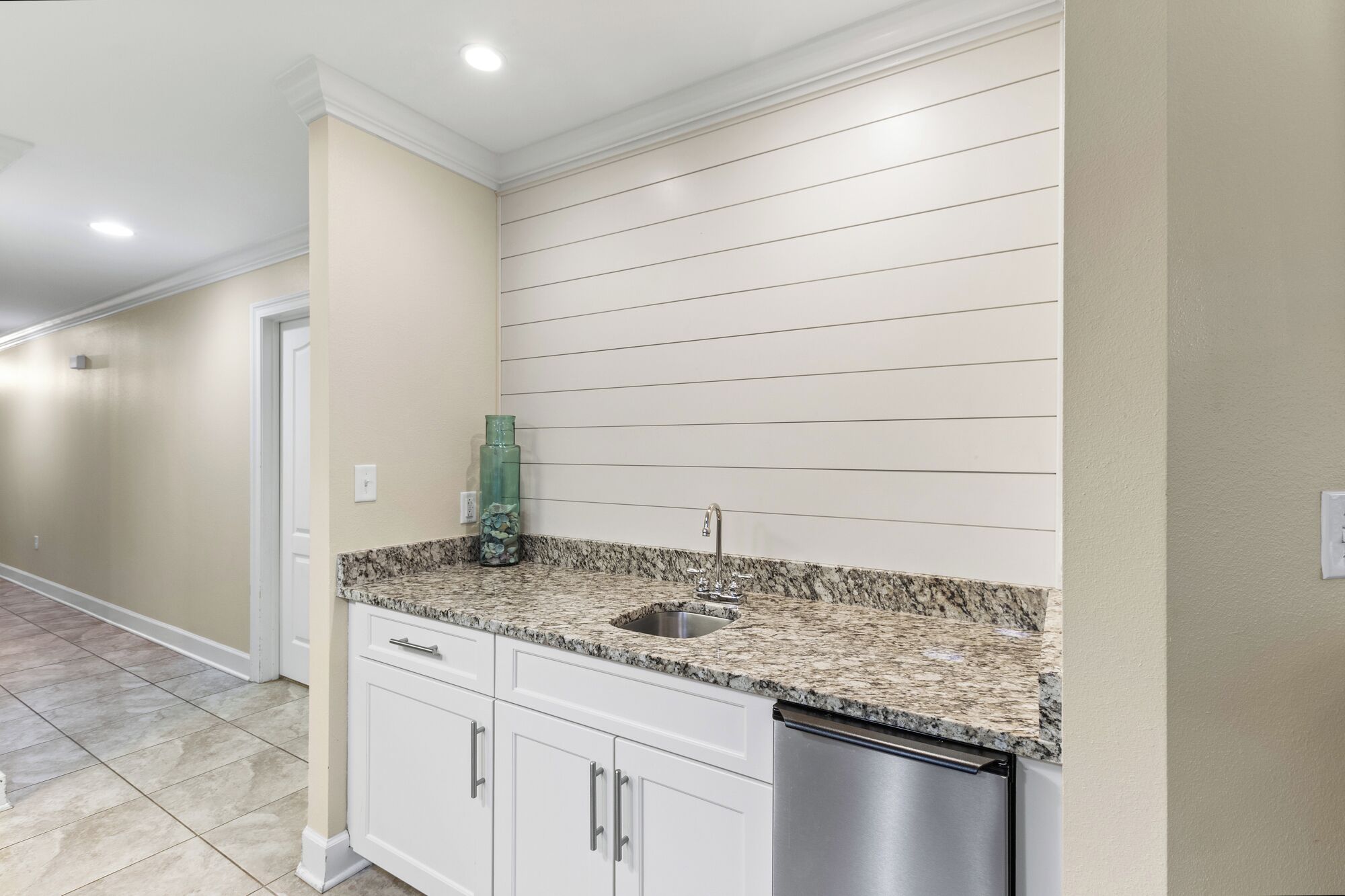 A kitchen with white cabinets, a granite countertop, a stainless steel dishwasher, and a double sink.