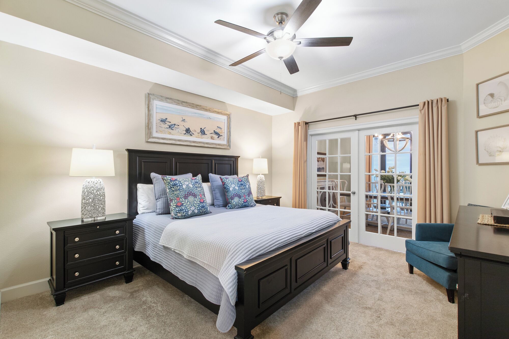 A bedroom with a bed, nightstands, a dresser, a ceiling fan, and a view through a glass door.