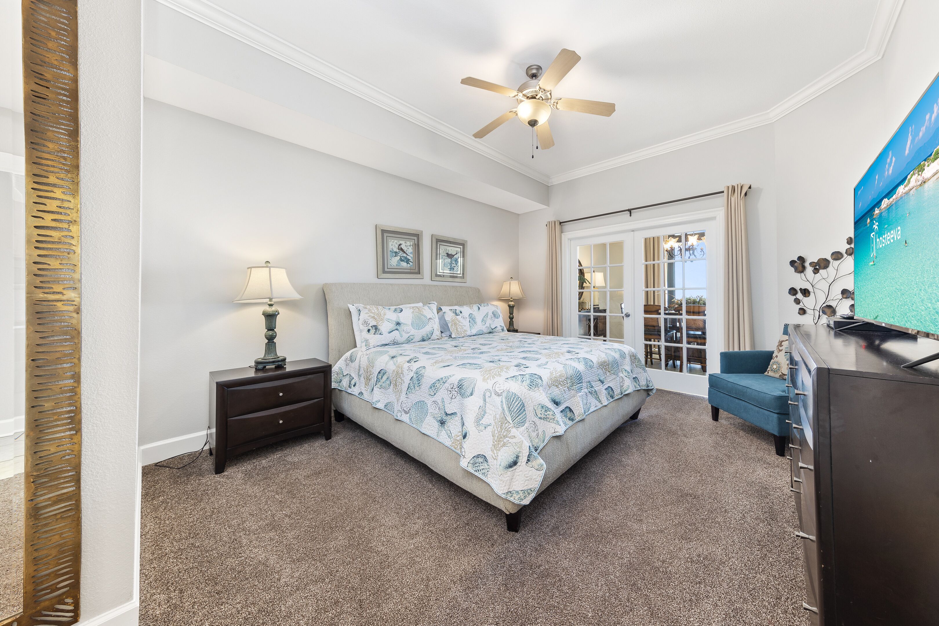 A bedroom with a bed, nightstands, a dresser, a ceiling fan, and a window with curtains.