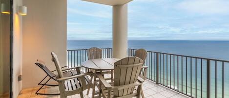 A balcony with a table and chairs, offering a view of the ocean.