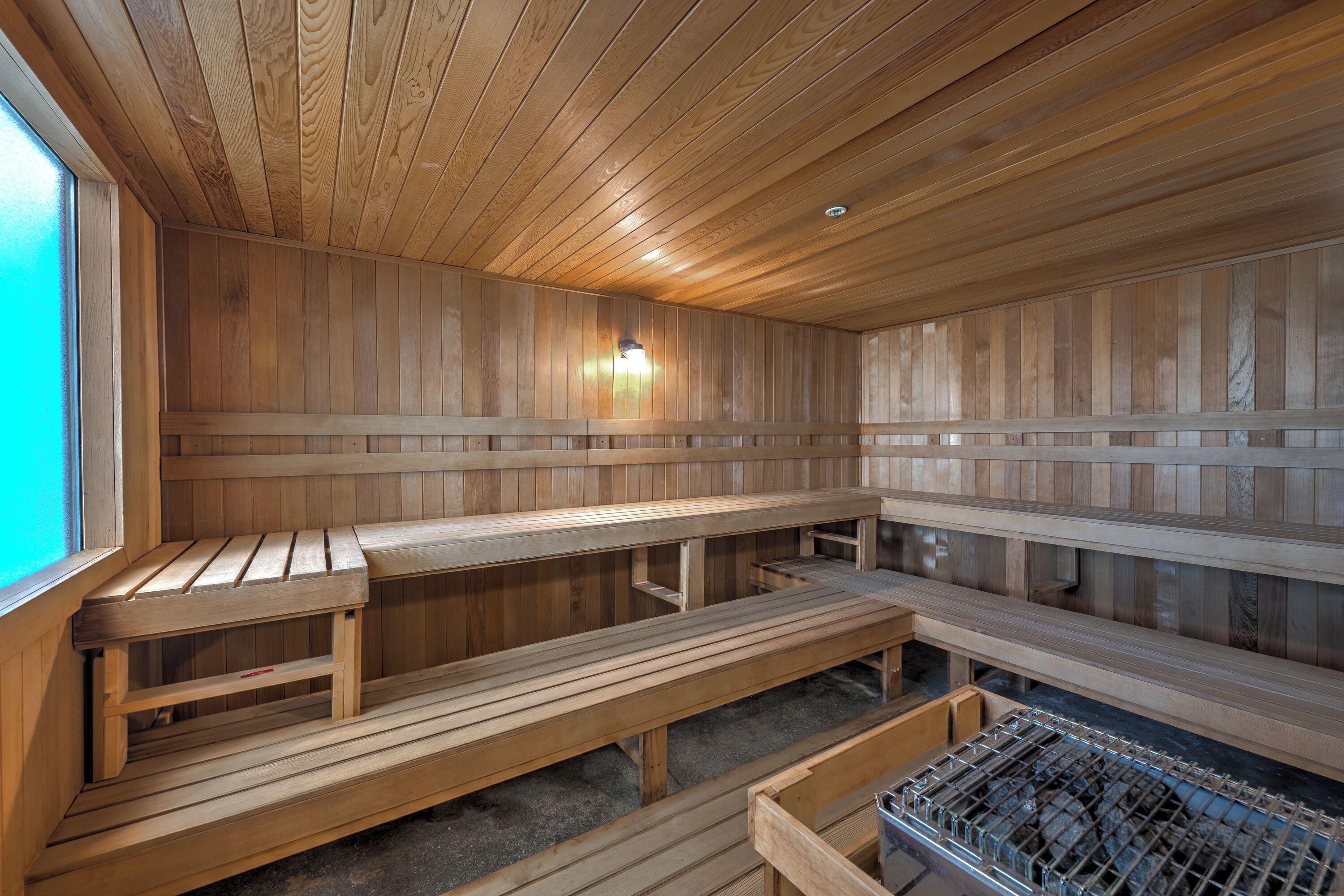 A sauna with wooden benches and a glass-walled section.