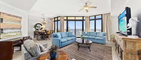 A spacious living room with a large window, a ceiling fan, and a television on a wooden cabinet.