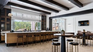 A modern kitchen with a bar area, large windows, and a view of the outdoors.