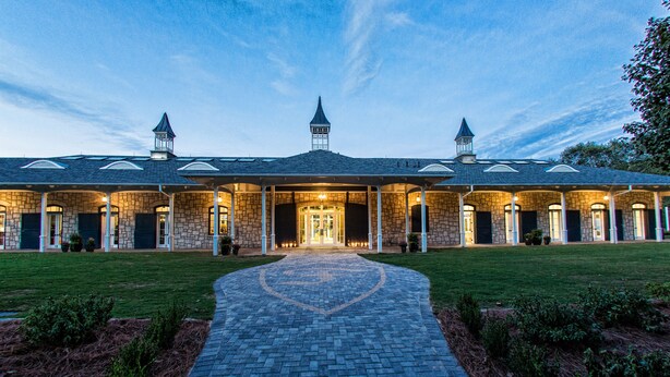 A large, stone building with a central entrance, multiple towers, and a well-maintained lawn.