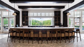 A modern kitchen with a large island, bar stools, and large windows offering a view of the outdoors.