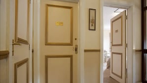 Un couloir avec trois portes, chacune dotée d’un cadre doré et, au-dessus de la porte de droite, une pancarte indiquant « The Grange 4 ».
