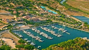 An aerial view of a marina with numerous boats docked, surrounded by residential buildings and greenery. - Argonauti Greenblu Resort (Pisticci)