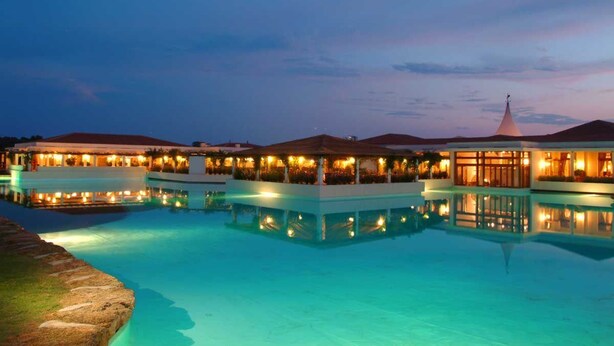 A resort with multiple swimming pools, connected by walkways, and surrounded by buildings with warm lighting. - Argonauti Greenblu Resort (Pisticci)