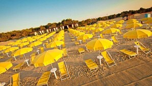 A beach with rows of yellow umbrellas and sun loungers. - Argonauti Greenblu Resort (Pisticci)