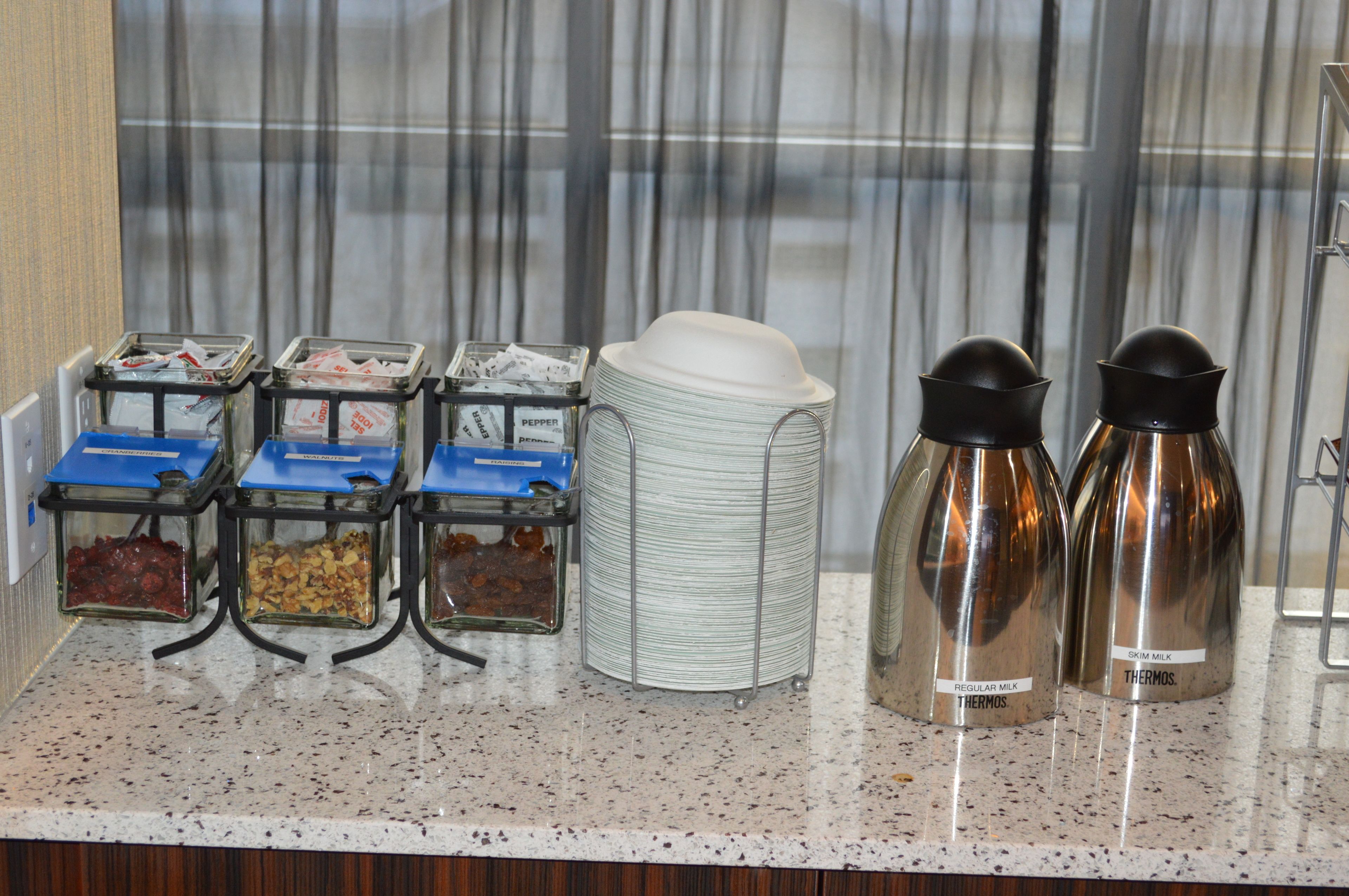 A breakfast bar with various food containers and thermos bottles.